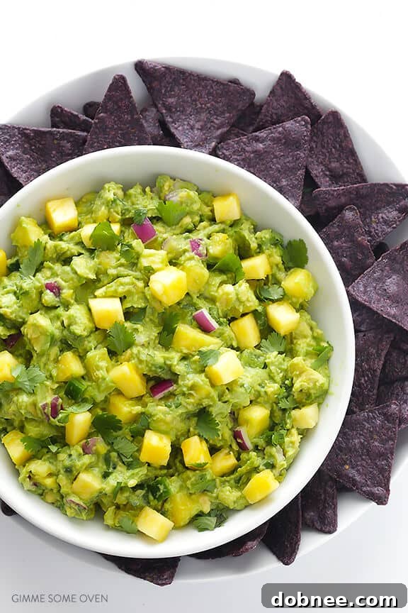 Friends enjoying pineapple guacamole and chips at a casual gathering, with hands reaching for the vibrant dip.