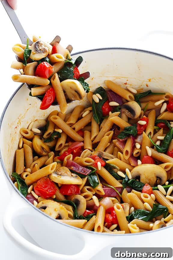 Delicious Pasta with Mushrooms, Tomatoes, and Spinach, tossed in a savory white wine garlic sauce – a quick and easy recipe perfect for any weeknight meal. Find this recipe at dobnee.com