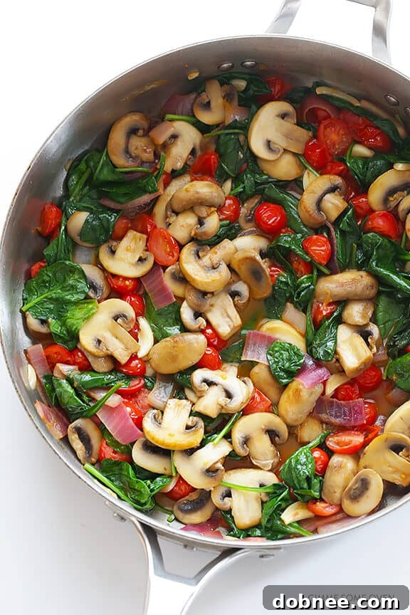 A vibrant bowl of Pasta with Mushrooms, Tomatoes and Spinach, highlighting the fresh ingredients and the savory white wine garlic sauce. A fast and healthy dinner idea. | dobnee.com