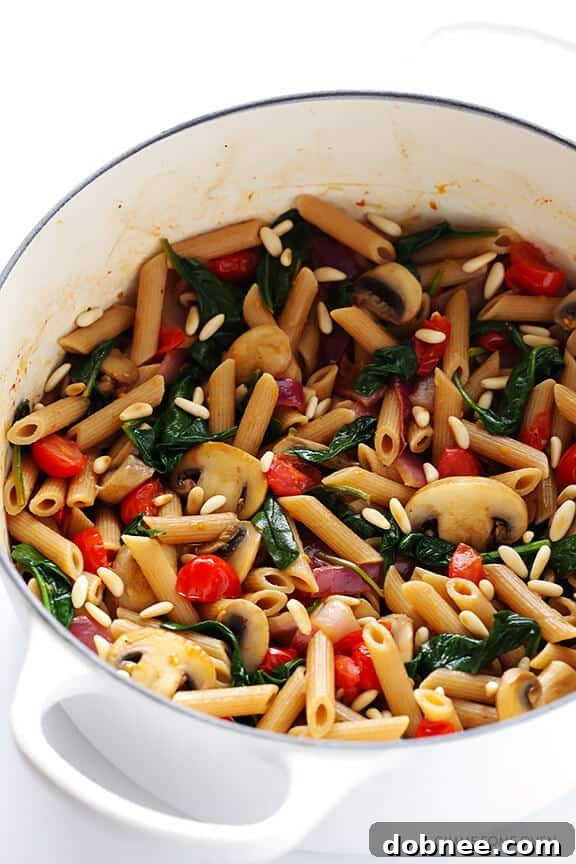 Freshly prepared ingredients for Pasta with Mushrooms, Tomatoes and Spinach, including whole wheat pasta, sliced mushrooms, and vibrant tomatoes. A quick vegetarian recipe. | dobnee.com