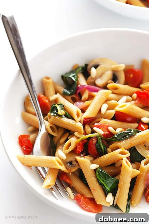 Final plating of Pasta with Mushrooms, Tomatoes and Spinach, garnished with toasted pine nuts, highlighting the rich flavors and fresh ingredients. An ideal quick and healthy meal. | dobnee.com