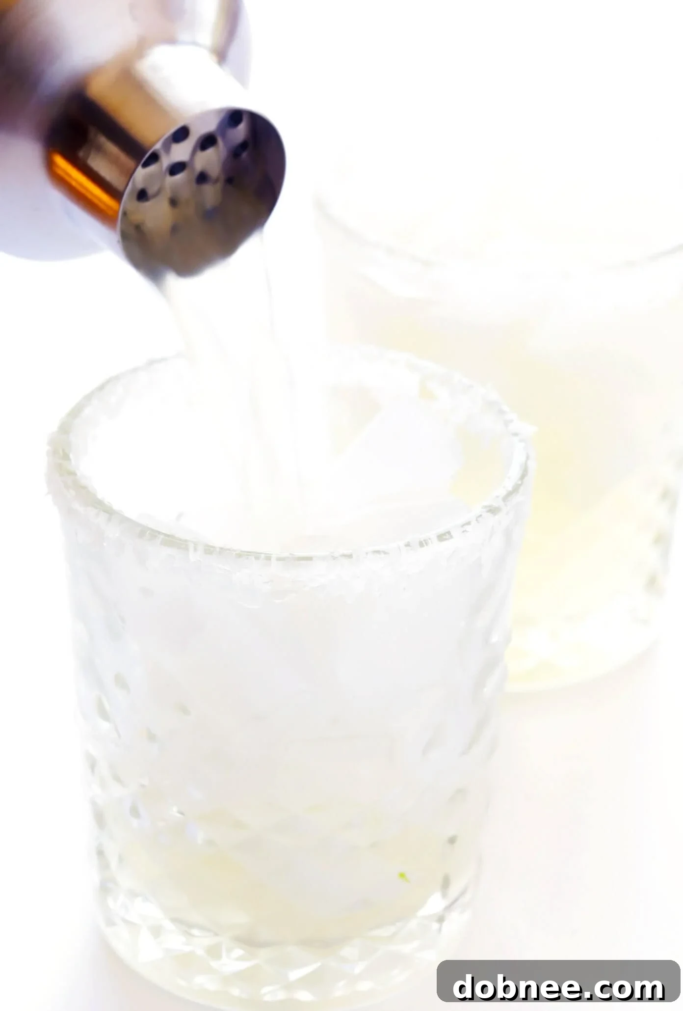 How to Make a Single Serving Margarita Straining a Margarita into a Glass with Ice