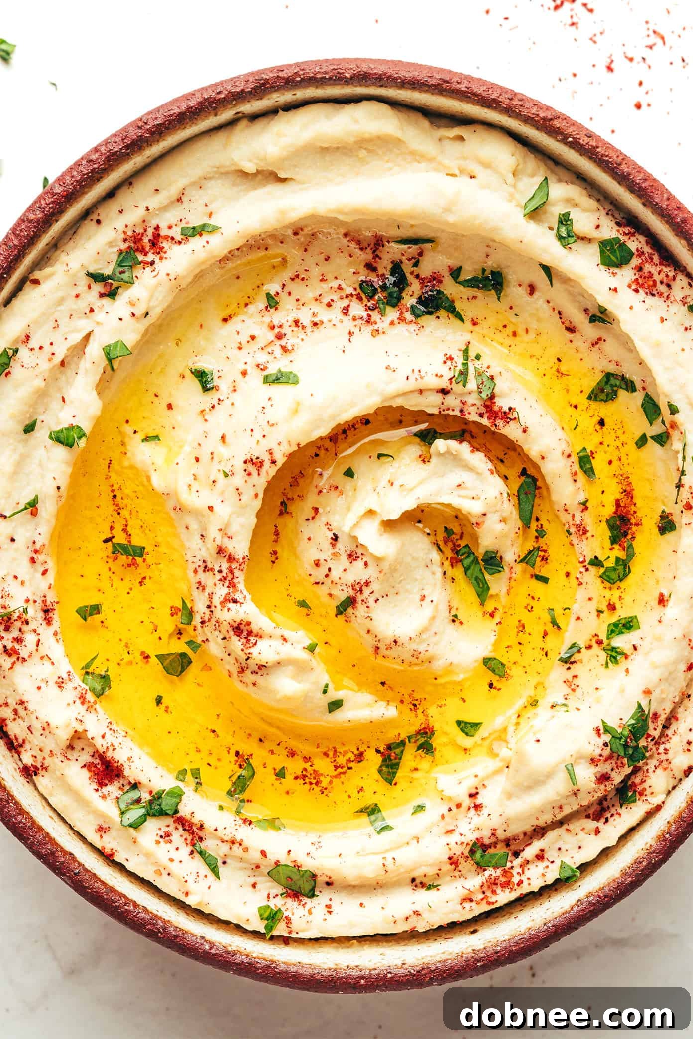 A bowl of homemade hummus, ready to be served with a spoon, highlighting its smooth and creamy texture.
