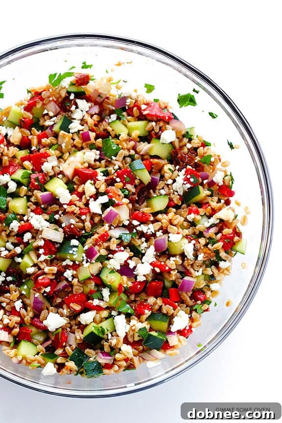 Mixing the Mediterranean Farro Salad in a large bowl with a Greek vinaigrette