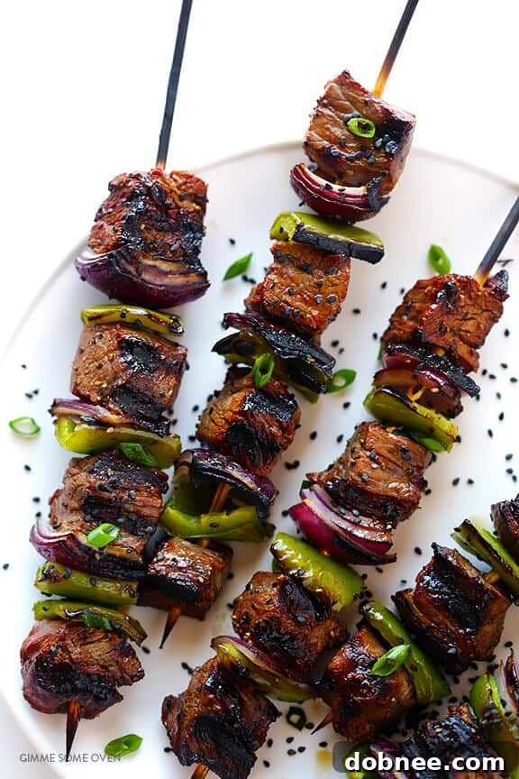 Asian Pepper Steak Kabobs sizzling on a hot grill, developing a beautiful char.