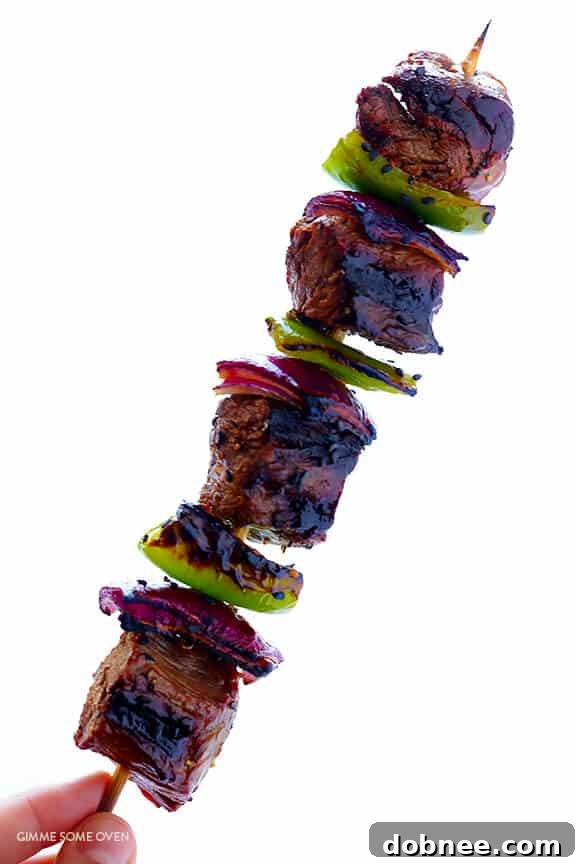 Grilled Asian Pepper Steak Kabobs brushed with a glossy sauce and garnished with sesame seeds.