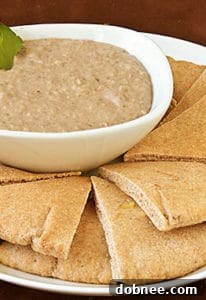 A close-up of creamy Black Bean Hummus in a bowl, garnished with a swirl of olive oil and fresh cilantro