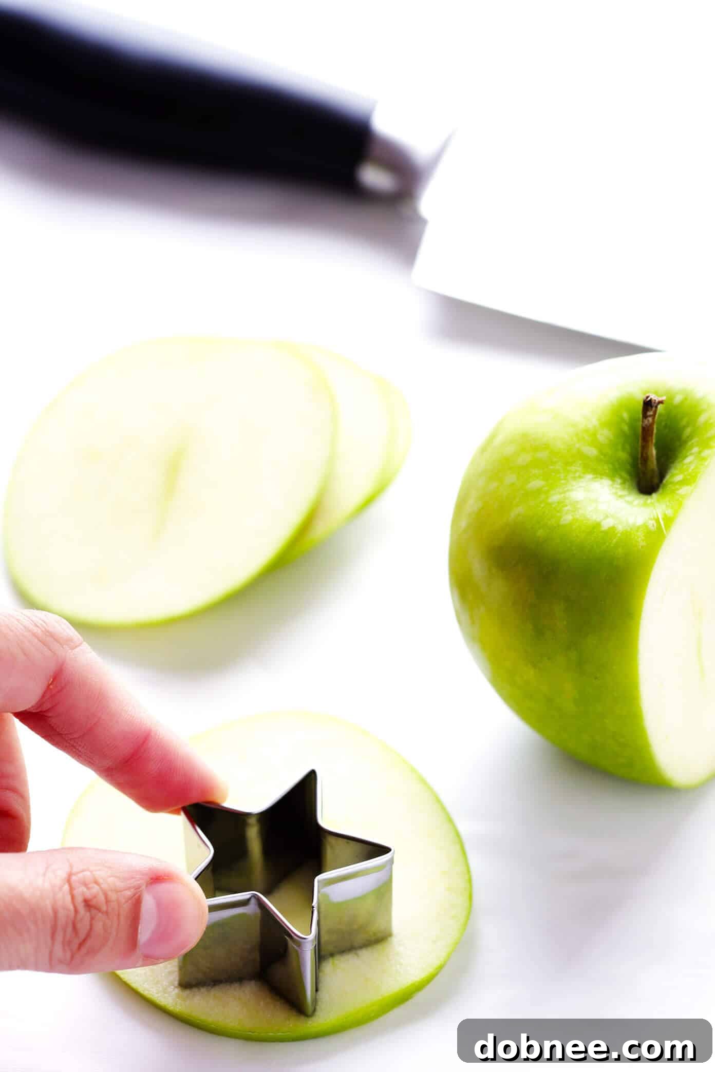 Apples expertly cut into star shapes, ready to be added to a Red, White, and Blue Sparkling Sangria recipe for an extra patriotic touch. Enhancing visual appeal for a 4th of July drink.