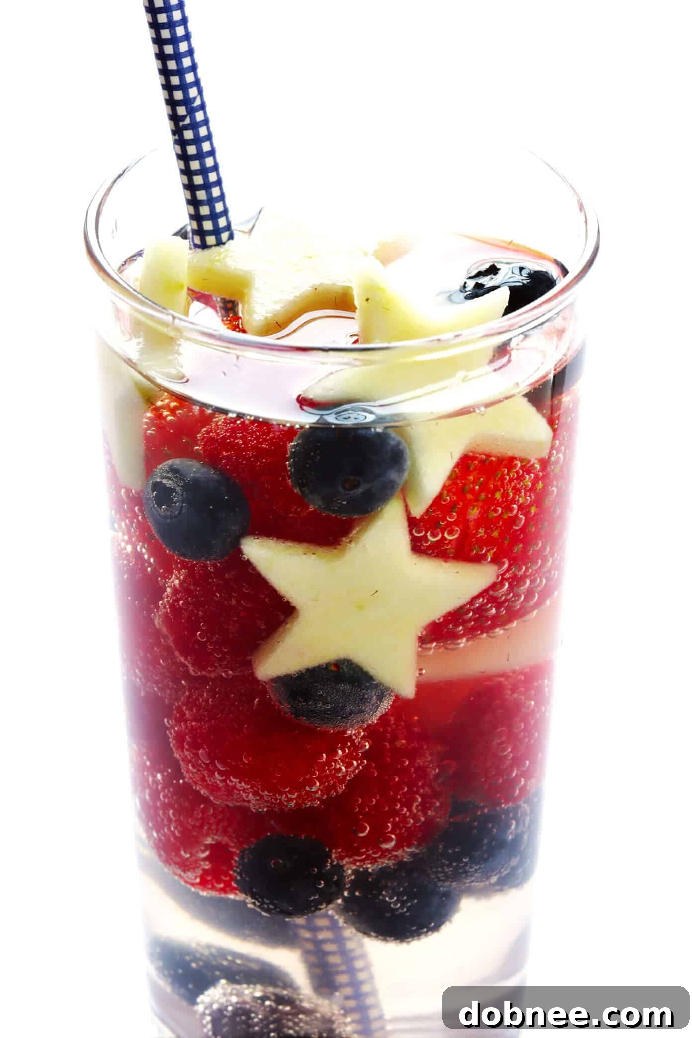 Individual glasses of Red, White, and Blue Sangria, garnished with fresh berries and apple stars, perfect for a 4th of July celebration. A refreshing and easy patriotic cocktail.