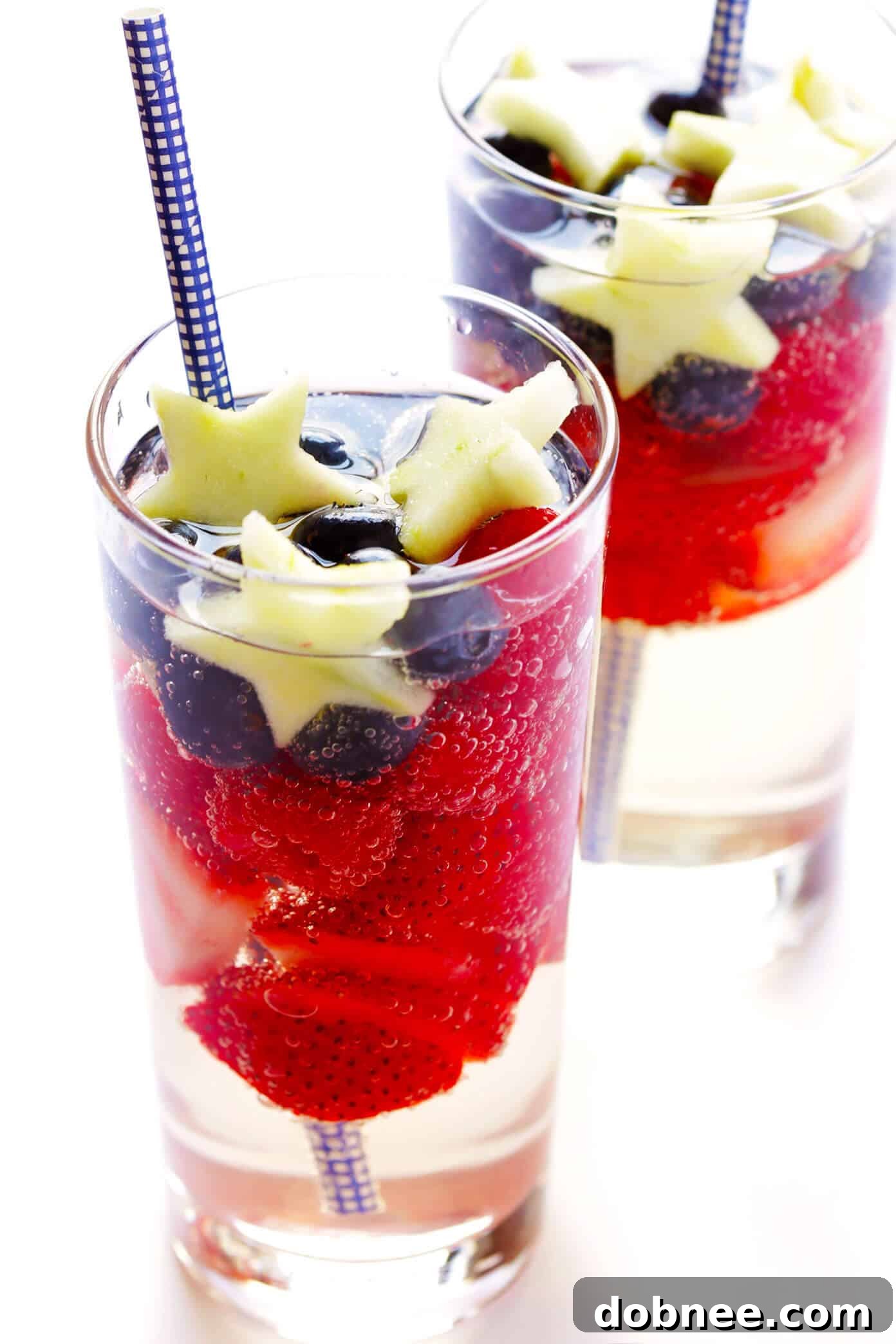 Close-up of Sparkling Red, White, and Blue Sangria in a glass, showcasing fresh fruit garnishes and effervescent bubbles. Ideal for summer patriotic celebrations.