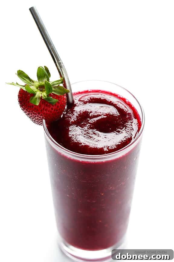 A hand holding a glass of Frozen Sangria outdoors in summer