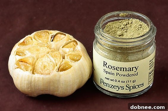 A second close-up image of the homemade Roasted Garlic, Rosemary & White Bean Hummus, showcasing its creamy texture and a decorative sprinkle of paprika.