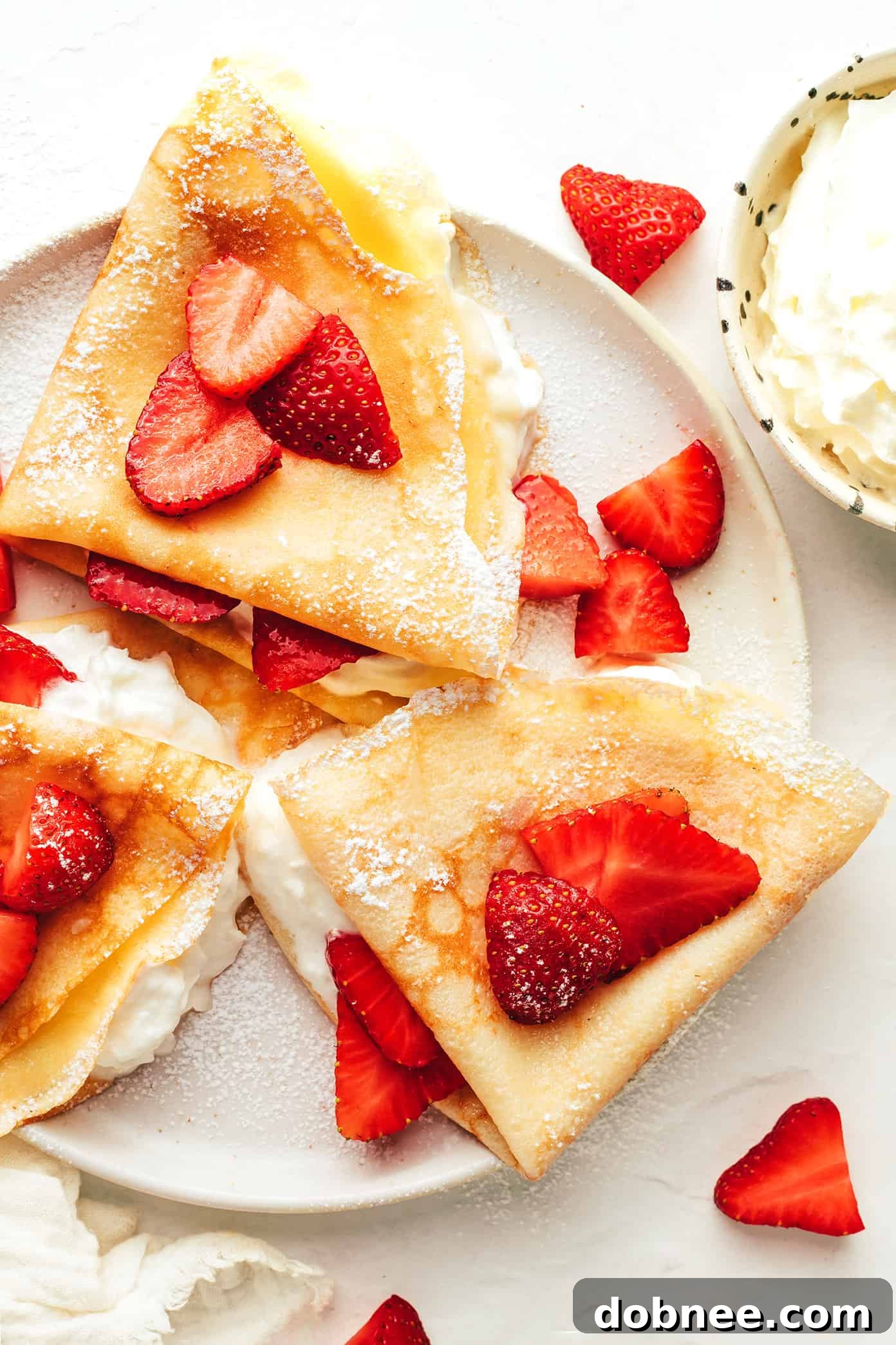 A stack of golden-brown French crepes on a white plate, ready to be filled.