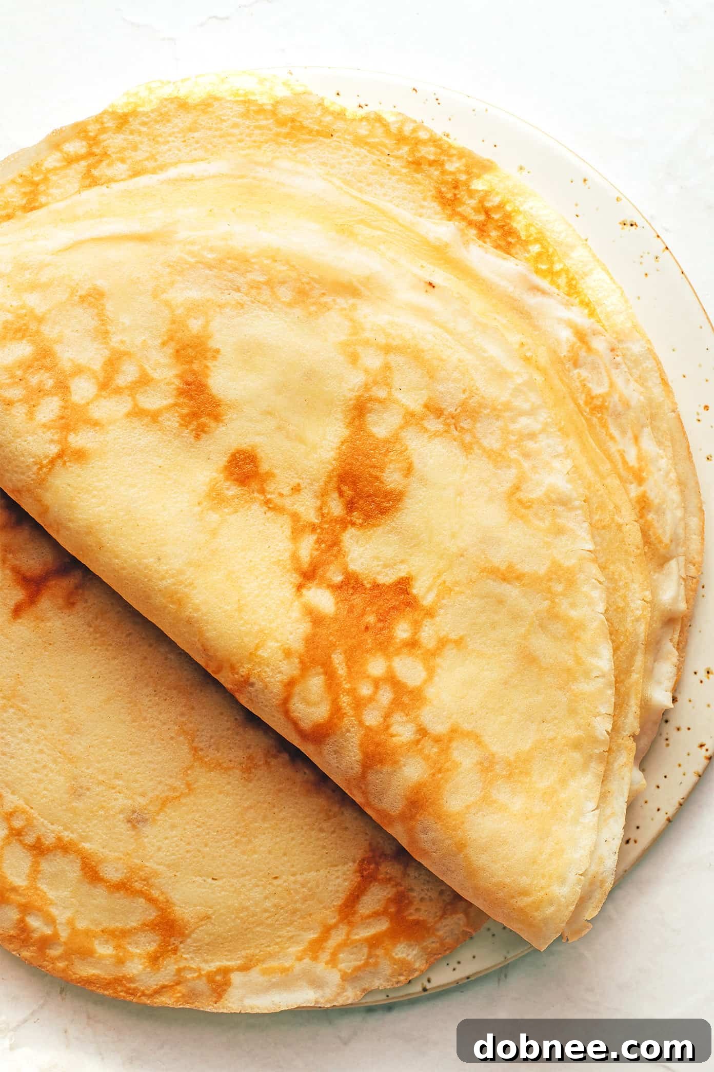 A close-up of a freshly made golden-brown crepe folded neatly on a plate.