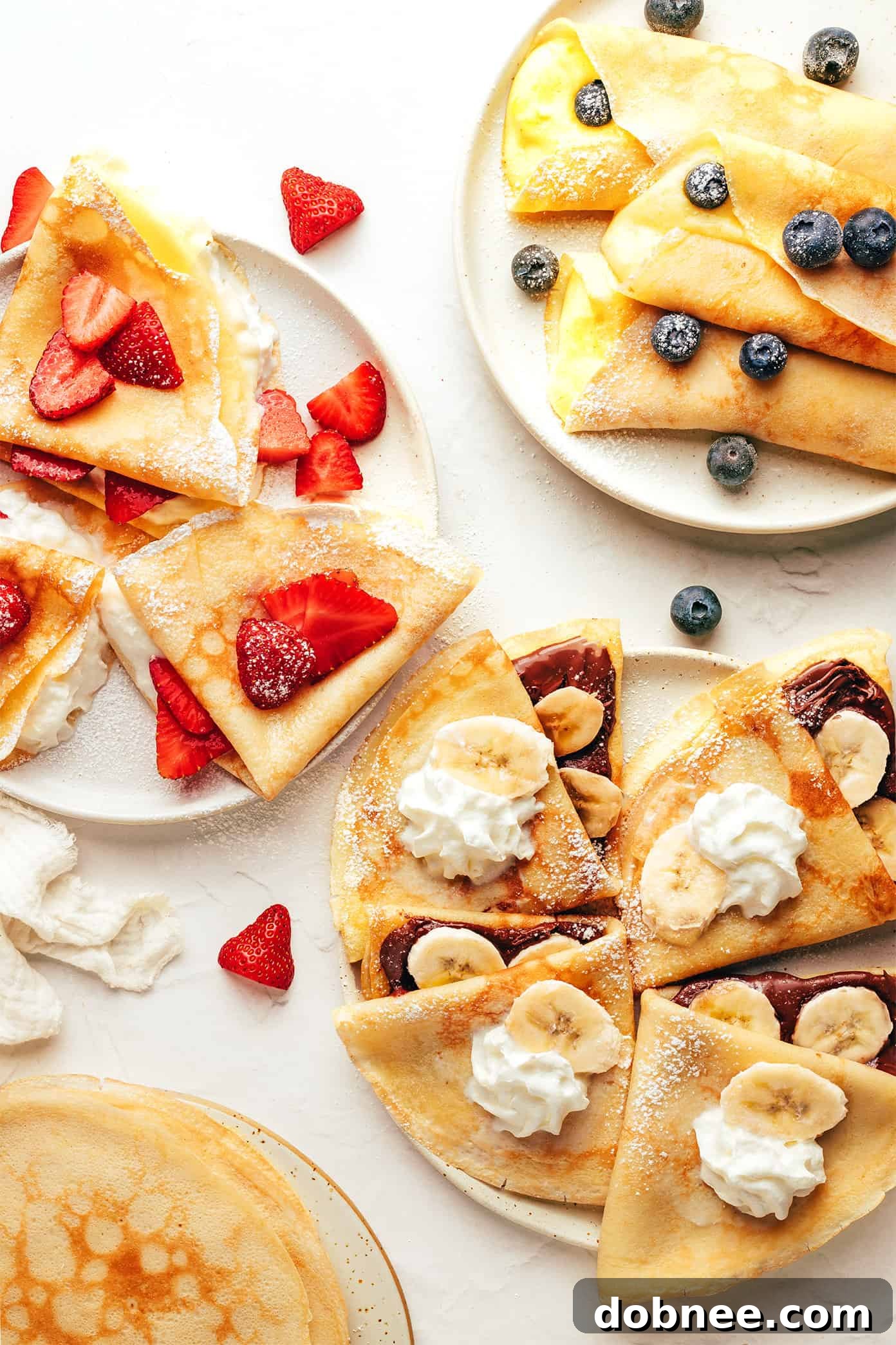 An artistic arrangement of various homemade crepes with different fillings, presented beautifully on a platter.