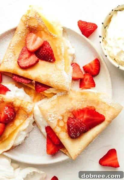 A stack of golden-brown French crepes on a white plate, ready to be filled.