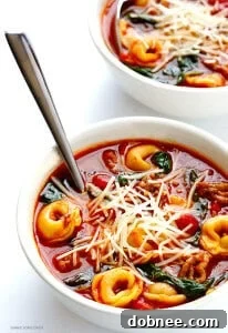A vibrant bowl of Italian Sausage Tortellini Soup, garnished with fresh basil.