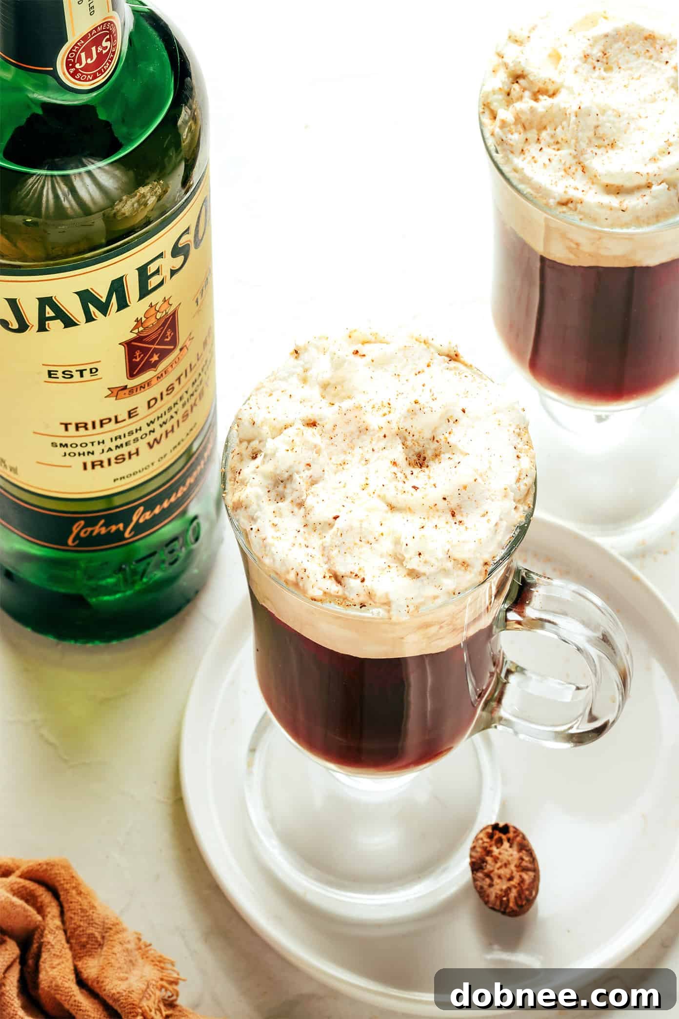 A warm mug of classic Irish Coffee, topped with a generous dollop of whipped cream and a sprinkle of chocolate shavings.