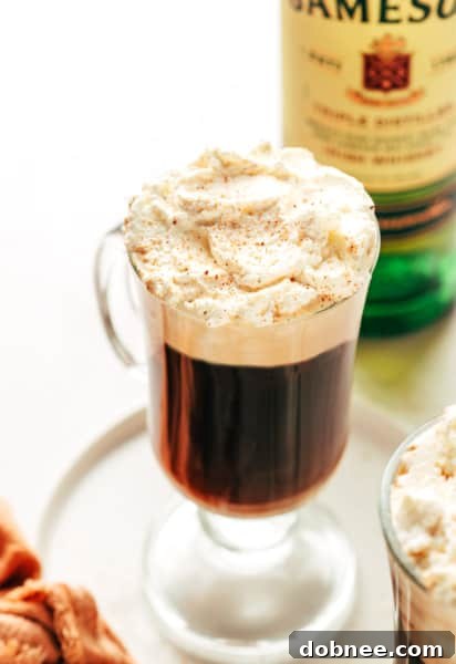 Classic Irish Coffee in a clear glass mug, topped with fluffy whipped cream and chocolate shavings.