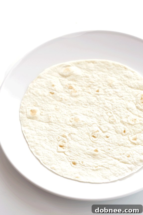 A pan filled with the savory potato, pepper, onion, and black bean hash, seasoned with green chiles and cumin, ready for the breakfast burritos.