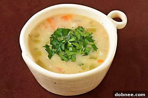 Close-up of creamy Roasted Garlic & Brie Soup with fresh herbs.