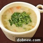 A small bowl of Roasted Garlic & Brie Soup, garnished with fresh parsley.