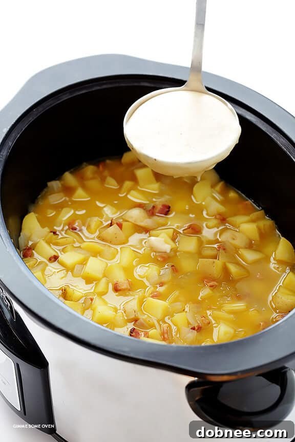 Diced potatoes, onion, and bacon simmering in a slow cooker with chicken stock, filling the kitchen with a delicious aroma