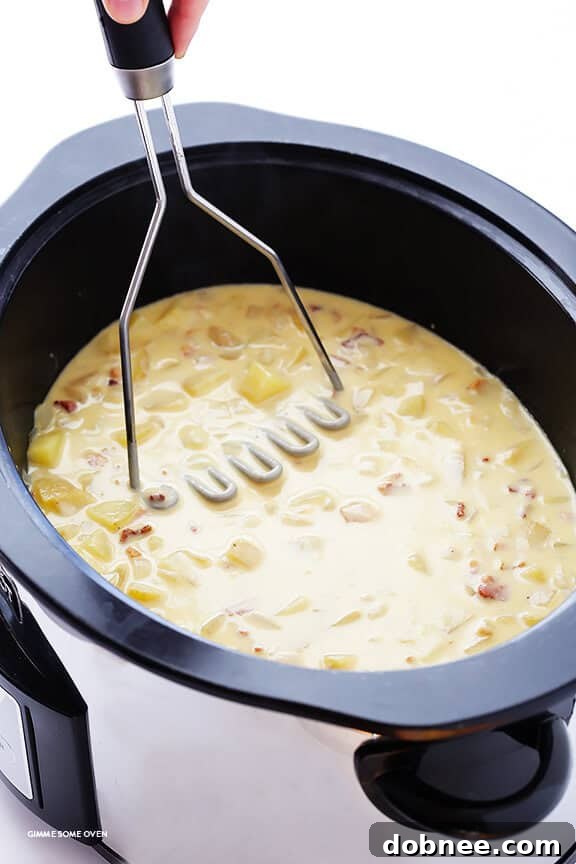 Roux being whisked in a saucepan with evaporated milk, thickening into a rich, creamy sauce for the potato soup