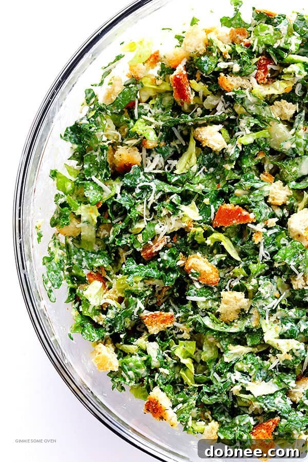 All the ingredients for Kale Caesar Salad, including kale, Romaine, Parmesan, and lime dressing, in a large mixing bowl.