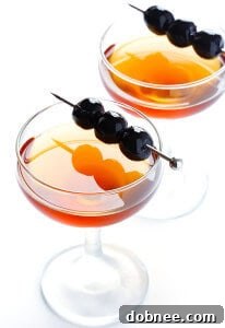 A classic Manhattan cocktail, rich amber in color, garnished with a single dark Luxardo cherry, in a coupe glass