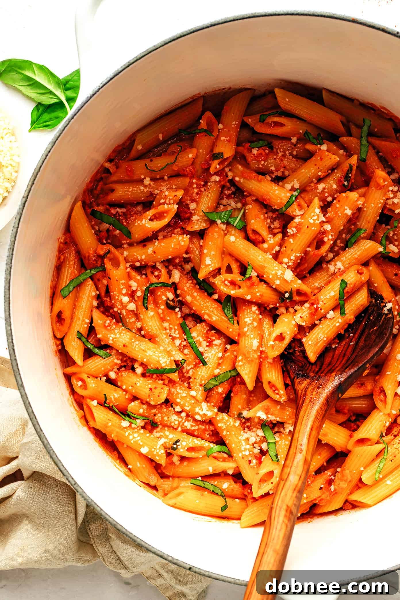 Velvety Vodka Penne 2 Classic Penne Alla Vodka pasta dish served in a bowl, garnished with fresh basil leaves and grated Parmesan cheese.