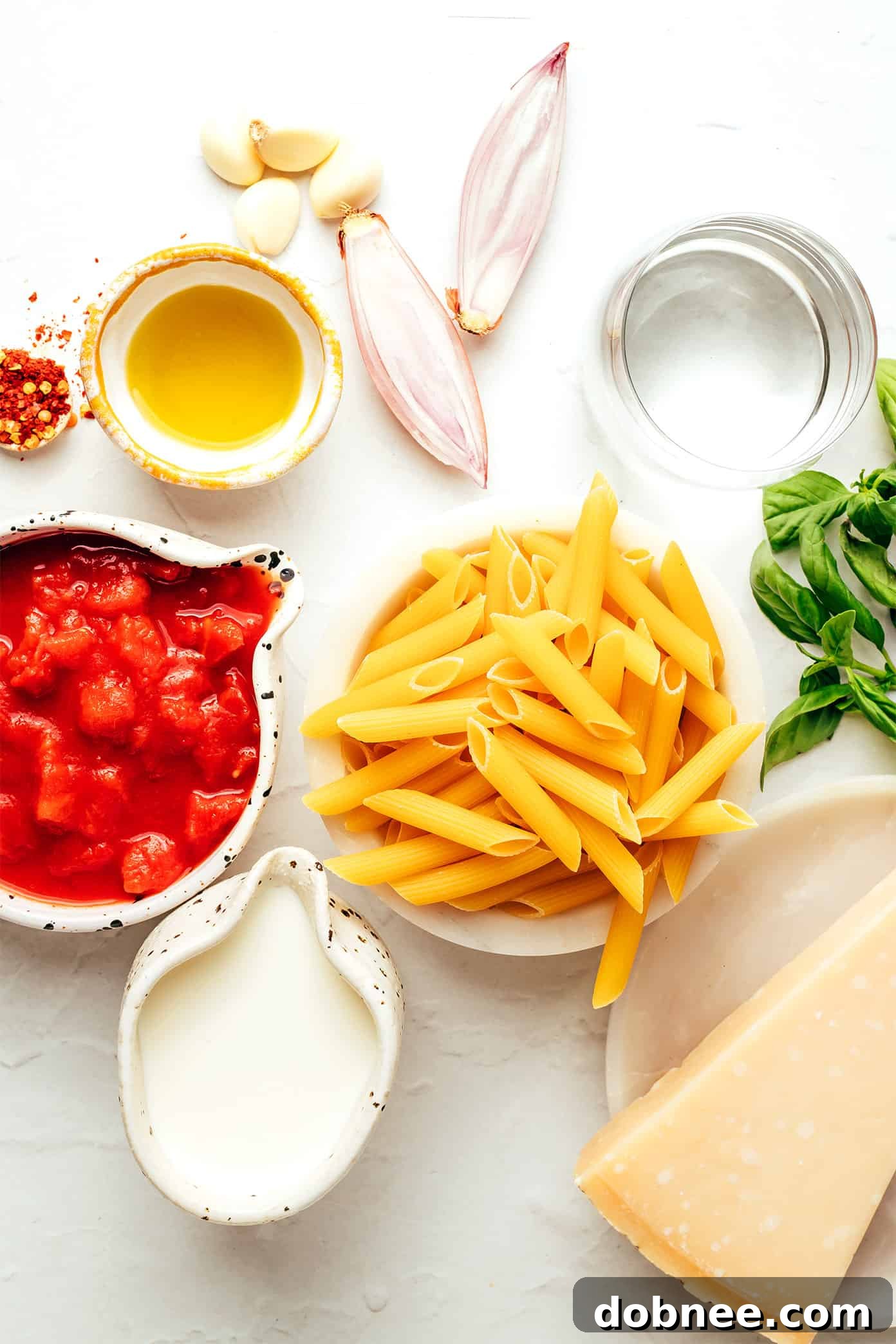 Velvety Vodka Penne 3 Fresh ingredients laid out for Penne Alla Vodka preparation, including ripe tomatoes, basil, and garlic.