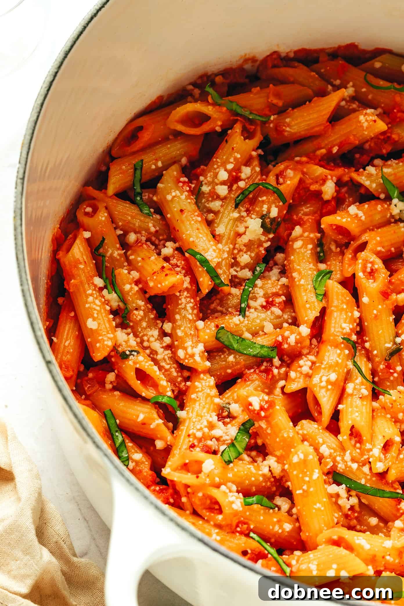 Velvety Vodka Penne 6 Crushed tomatoes being added to the simmering vodka and aromatic mixture, creating a vibrant red sauce.