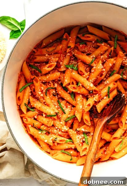 A vibrant, creamy Penne Alla Vodka pasta dish, garnished with fresh basil leaves.
