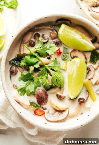 Tom Kha Gai in a bowl with cilantro and lime