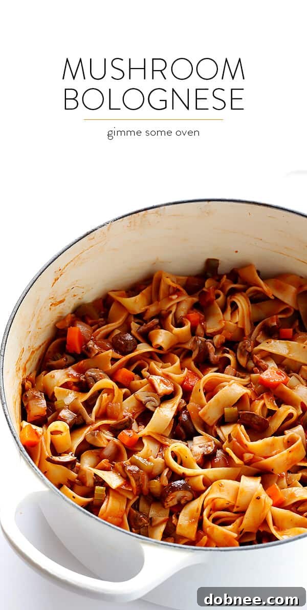 A top-down view of Mushroom Bolognese pasta in a large bowl, garnished with fresh herbs and Parmesan cheese.