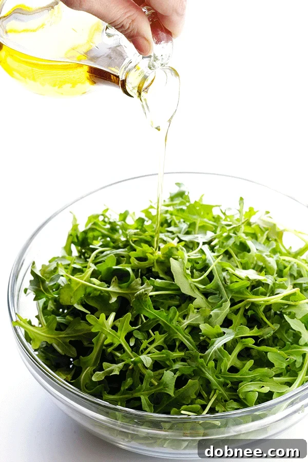 Hand grating Parmesan cheese over the 5-Ingredient Arugula Salad, demonstrating the simple preparation.
