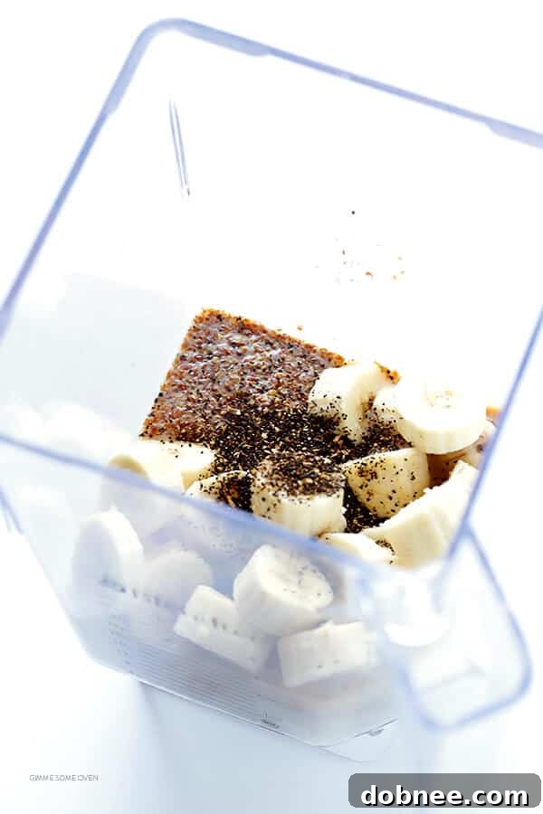 Blending ingredients for a Banana Chai Smoothie: frozen bananas, almond milk, Greek yogurt, chai, vanilla, and cinnamon.