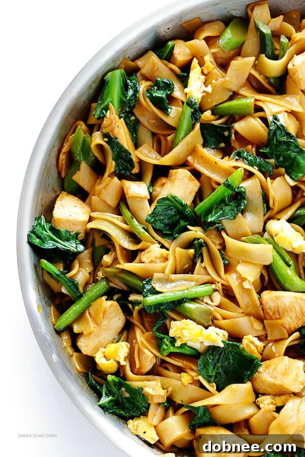 A vibrant plate of Pad See Ew, showcasing its rich brown sauce, wide noodles, chicken, and fresh green Chinese broccoli.