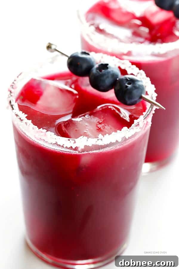 Vibrant Blueberry Margaritas served in a salt-rimmed glass, garnished with fresh blueberries and lime. Perfect for Cinco de Mayo celebrations.