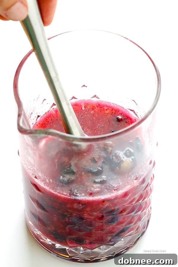 The process of muddling blueberries and lime juice for a homemade margarita base.