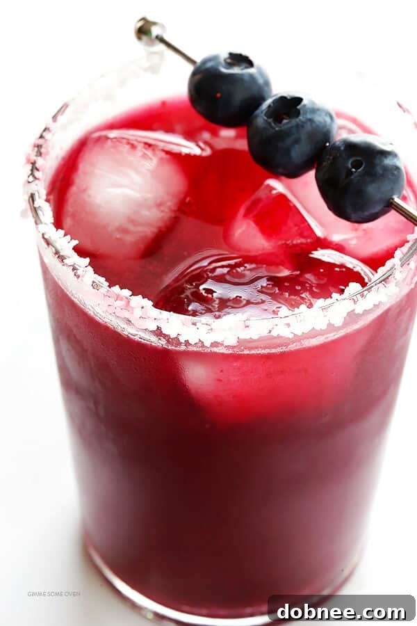 Mixing blueberry puree with tequila and orange liqueur in a cocktail shaker.