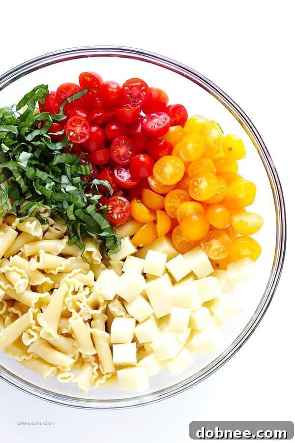 Close-up of fresh Caprese Pasta Salad, highlighting ripe cherry tomatoes, mini mozzarella balls, and vibrant basil leaves.