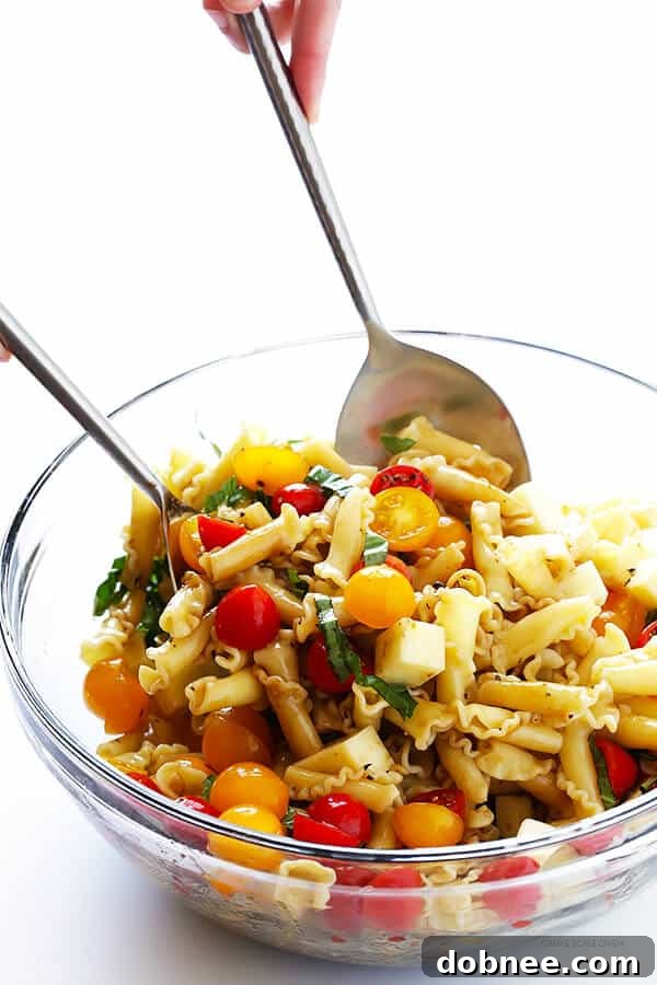 Ingredients for Caprese Pasta Salad neatly arranged: cooked pasta, halved cherry tomatoes, fresh mozzarella pearls, and basil leaves.