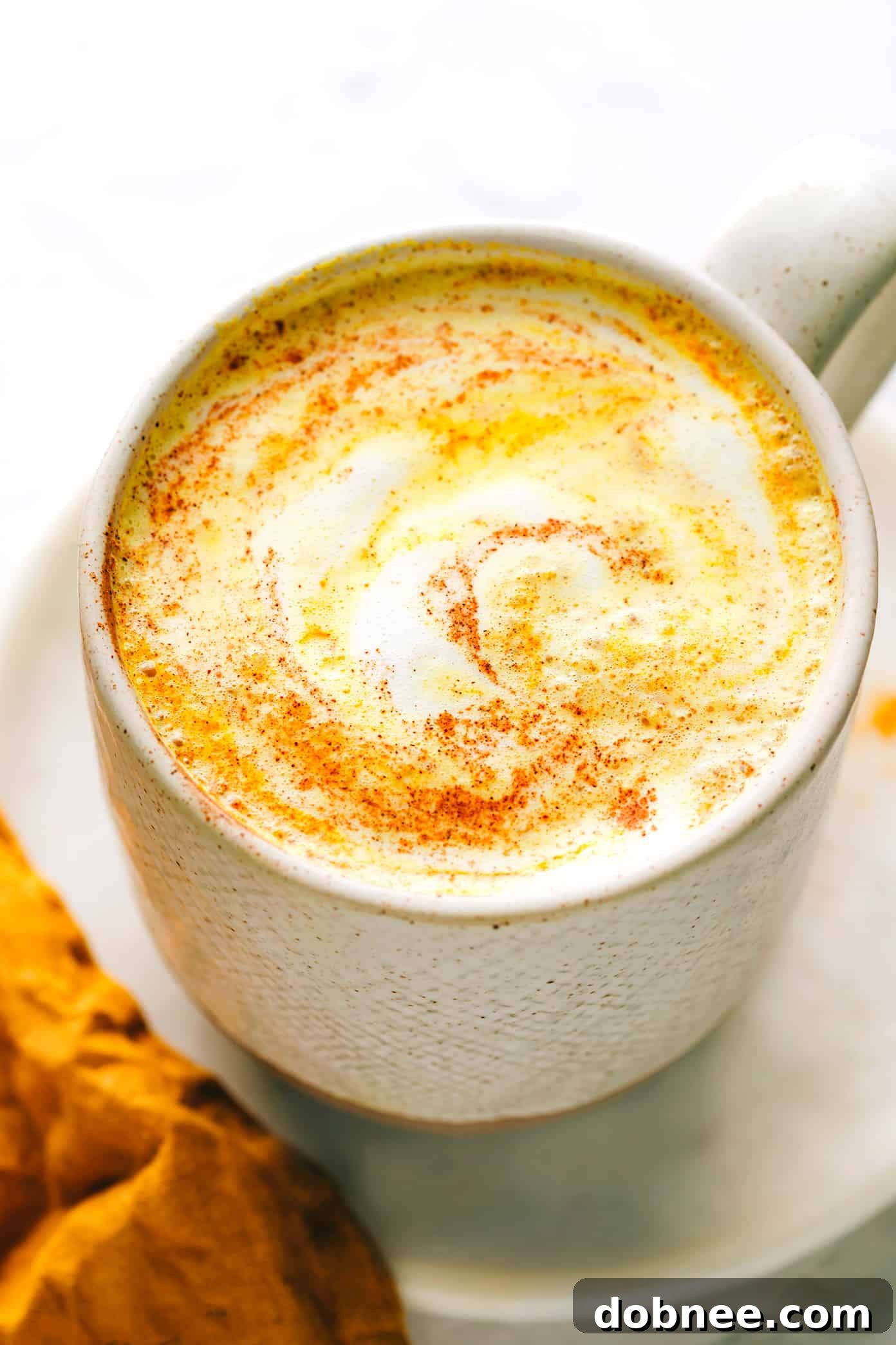 A beautifully presented golden milk latte, garnished with a sprinkle of cinnamon, in a cozy setting.