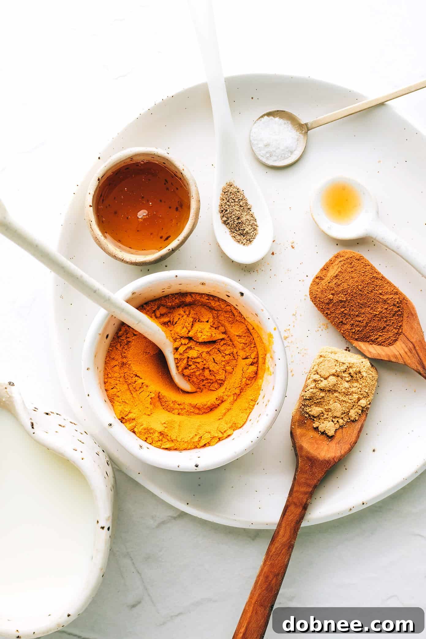 Golden milk ingredients arranged beautifully: various spices, milk, and sweetener, ready for preparation.