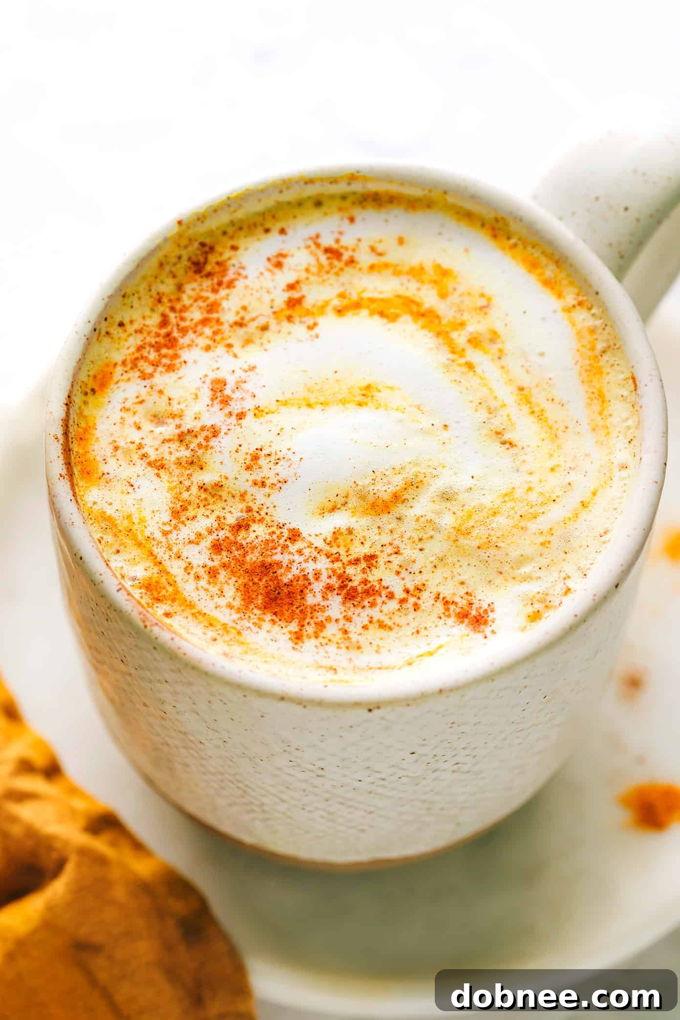 A serene shot of golden milk in a glass, with a spoon resting beside it, highlighting the vibrant color.