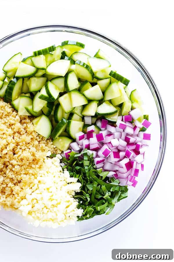 Close-up of freshly chopped English cucumber, red onion, and basil, ready to be mixed for a refreshing salad.