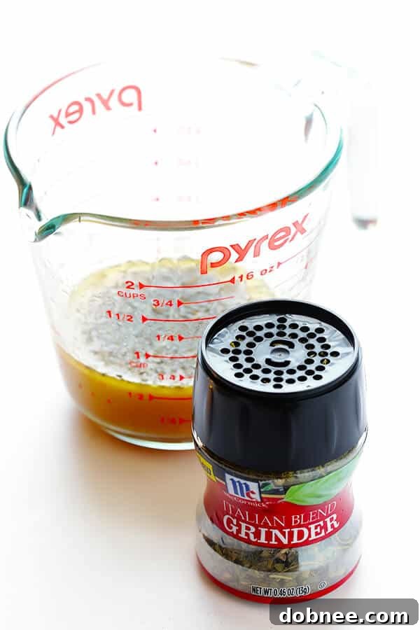 Pouring homemade Italian herb vinaigrette over the pasta salad ingredients