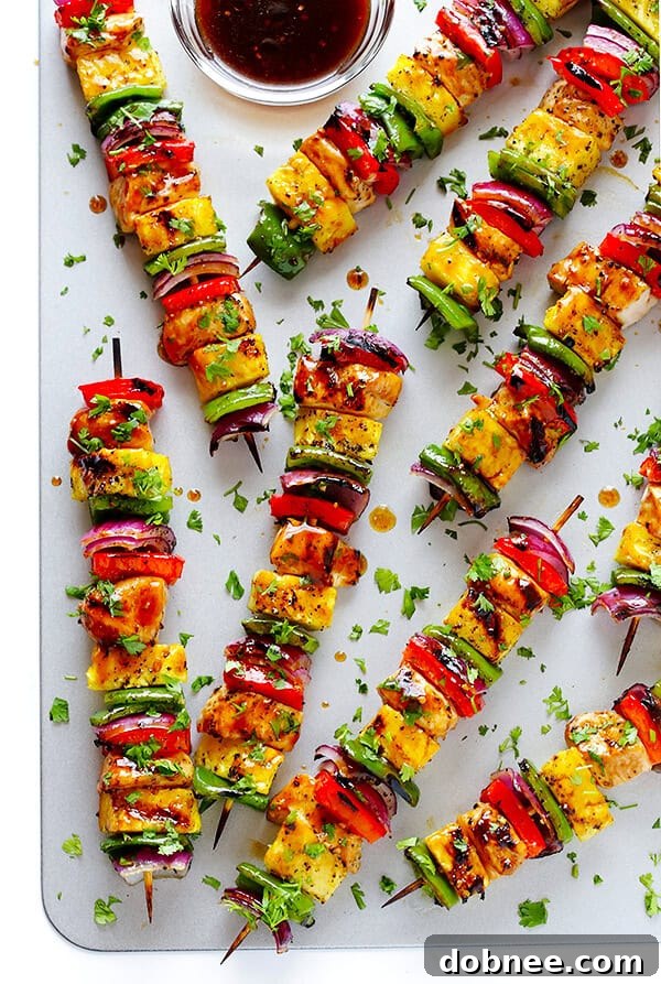 Grilled Rainbow Hawaiian Chicken Kabobs with a citrus teriyaki marinade, colorful bell peppers, and pineapple, sprinkled with fresh cilantro.